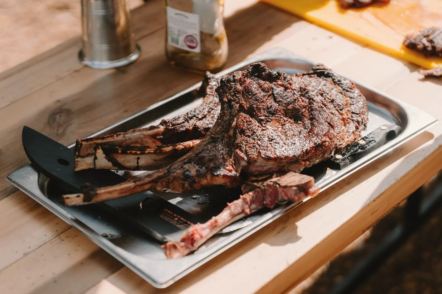 A large rib of beef resting on a tray in a working kitchen