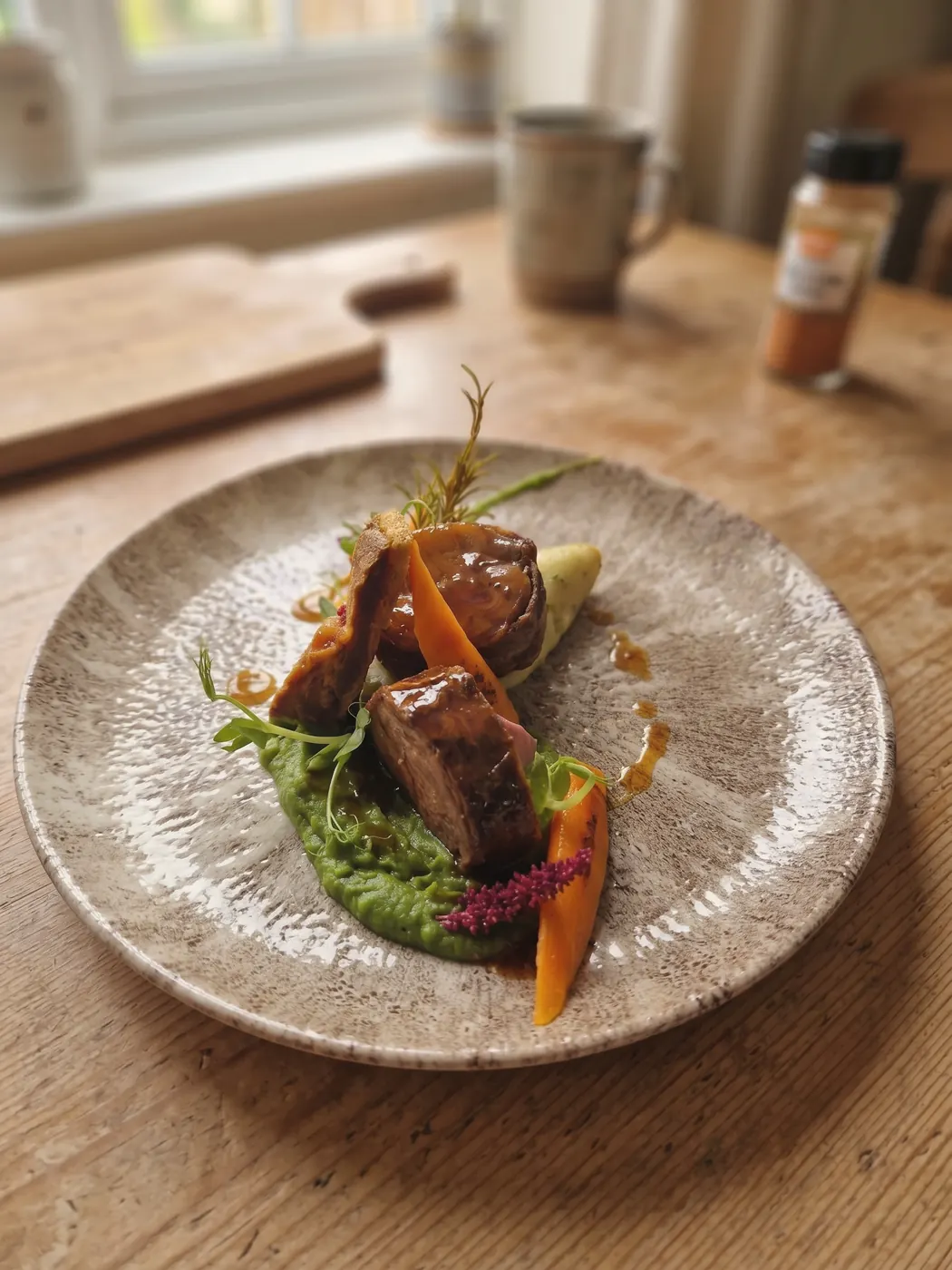 A glazed main course plated on a speckled stoneware plate on a wooden table
