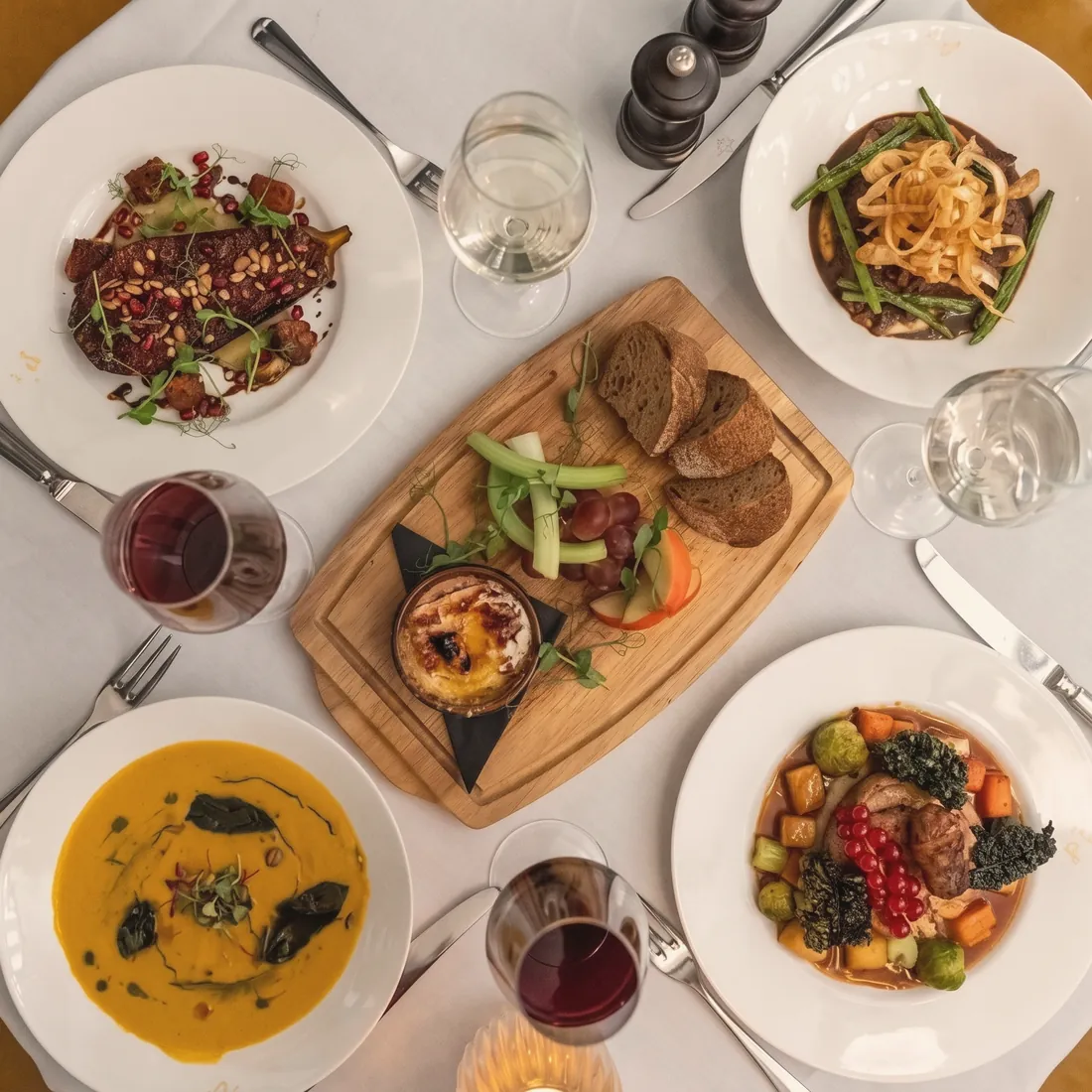 Mesa completa con platos servidos, pan, queso y vino, servida por un chef privado en Gran Canaria